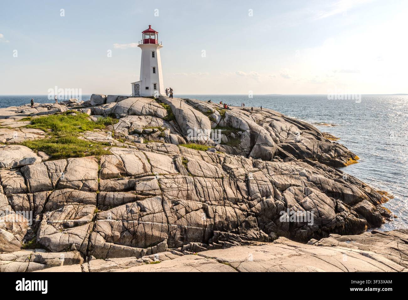 Besucher auf den Granitklippen um den Leuchtturm in Peggy’s Cove, Halifax Regional Municipality, Nova Scotia, Kanada. Der heutige Leuchtturm, aus Beton und Stahl gebaut, wurde 1915 in Betrieb genommen und ersetzte einen hölzernen Vorgänger aus dem Jahr 1868. Halifax Regional, Nova Scotia, Kanada Stockfoto