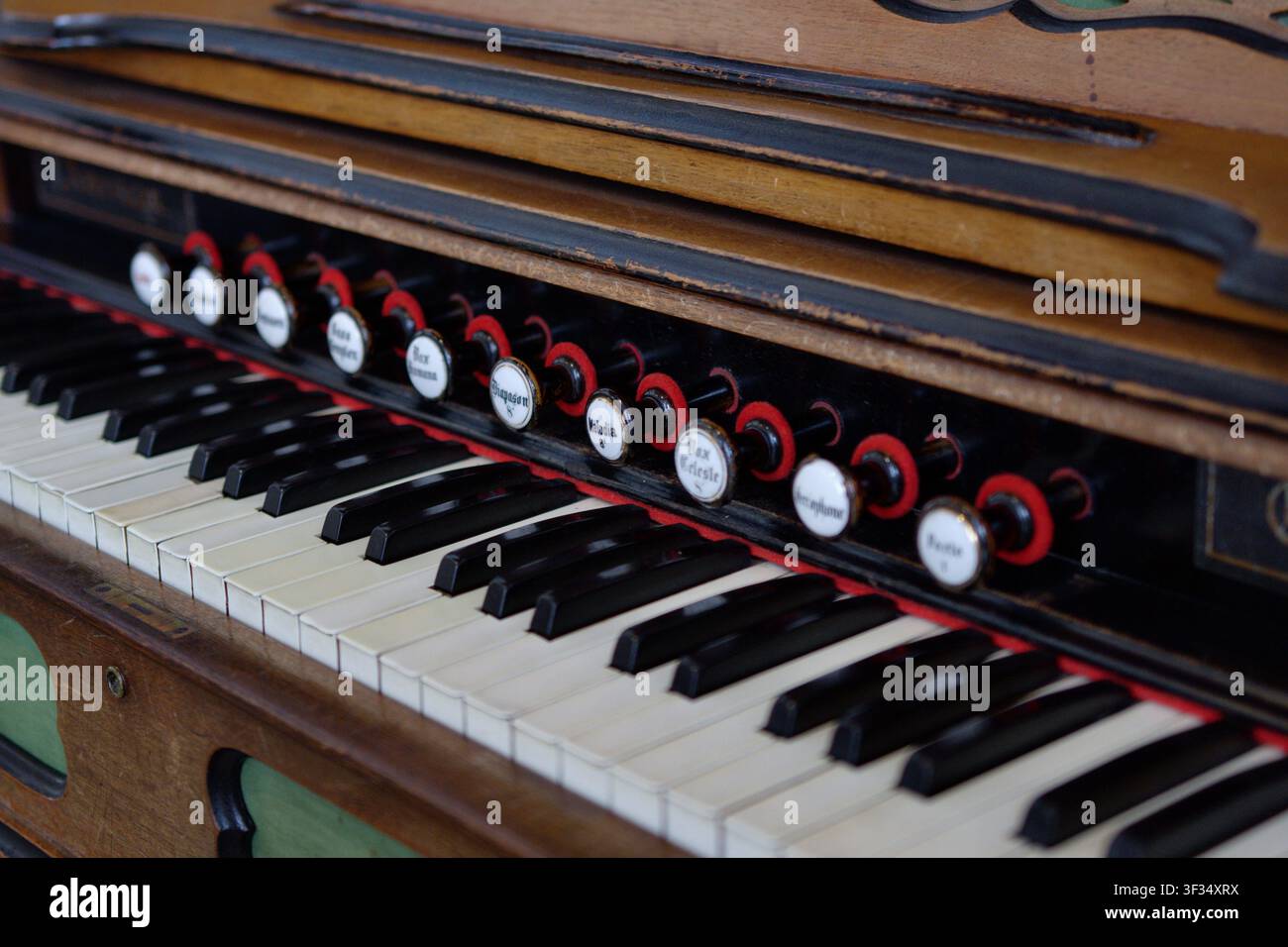 Nahaufnahme der Tastatur und Stoppsteuerungen eines traditionellen Harmonium, die seine Holzhandwerkskunst und historisches Musikdesign hervorheben. Stockfoto
