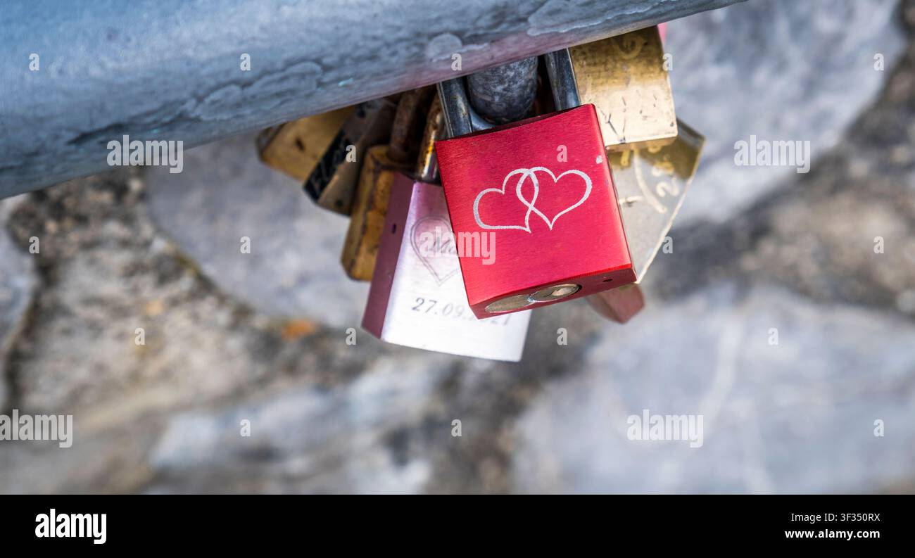 Vorhängeschlösser, die ewige Liebe und Treue symbolisieren, an einem Metallgeländer befestigt. Eine romantische Tradition für Paare Stockfoto