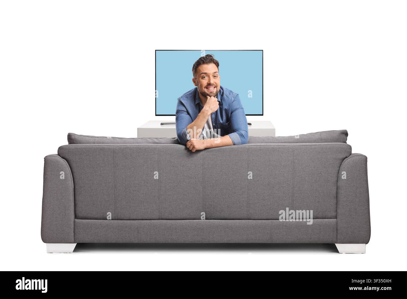 Mann lehnt sich auf einem grauen Sofa vor einem Fernsehgerät Stockfoto