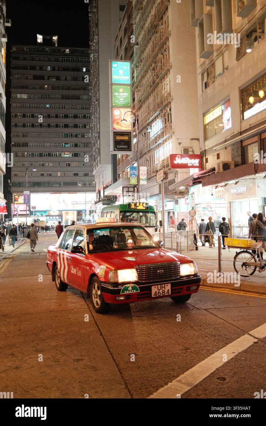 Ikonisches rotes und weißes städtisches Taxi, das auf einer Stadtstraße fährt, Hongkong, China. Stockfoto