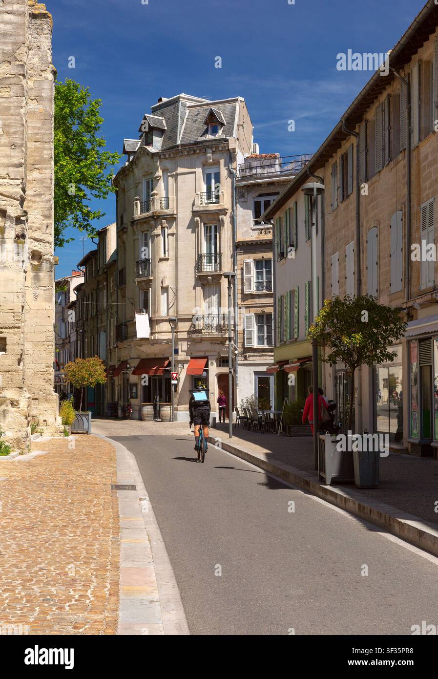 Ansicht einer historischen Straße mit traditioneller Architektur und einem Radfahrer in Avignon, Provence, Frankreich. Stockfoto