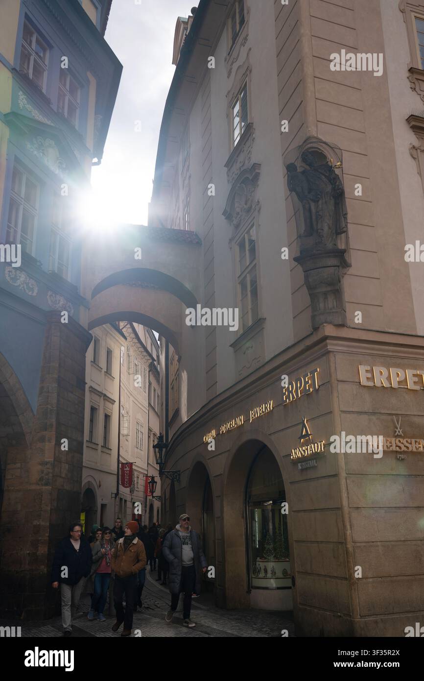 Fußgänger gehen unter historischen Stützbögen auf der Melantrichova Straße neben markierten Kristall- und Porzellangeschäften in der Prager Altstadt, Tschechische Republik Stockfoto