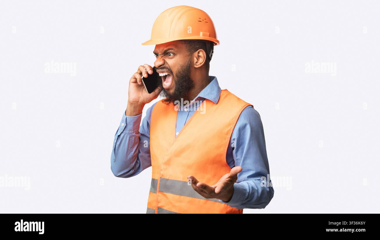 Angry Builder Schreit In Handy Stehen In Studio, Panorama Stockfoto