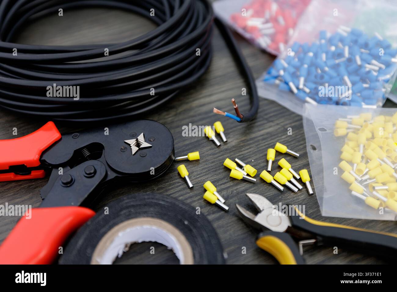 Eine Sammlung von Elektrikerwerkzeugen, darunter Drahtabisolierer, Verbinder und Kabel, die für elektrische Verkabelung und Kommunikationsinstallationen unerlässlich sind. Stockfoto