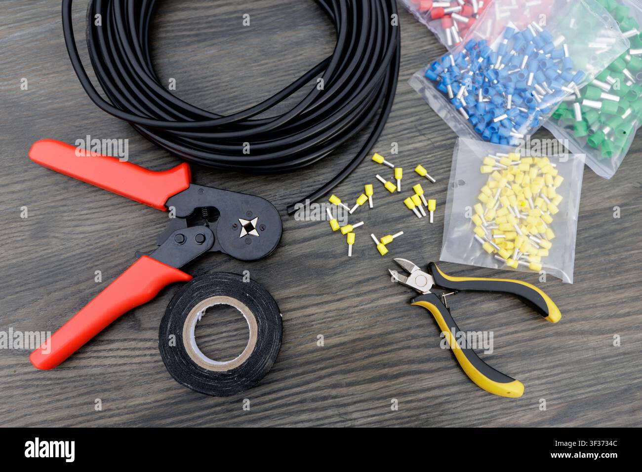 Ein Sortiment an wesentlichen Elektrikerwerkzeugen einschließlich Abisolierwerkzeugen, Isolierband und Steckverbindern, perfekt für Verkabelungs- und Kommunikationsprojekte. Stockfoto