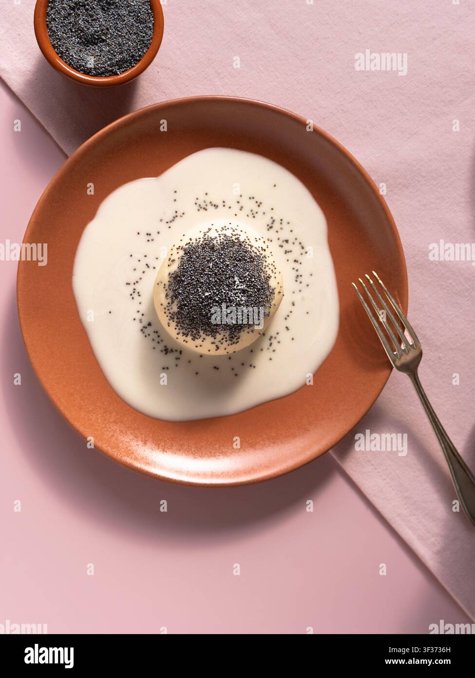 Minimalistische Lebensmittelaufnahme mit süßem deutschem Knödel, garniert mit Mohnseeds und cremiger Vanillesauce Stockfoto