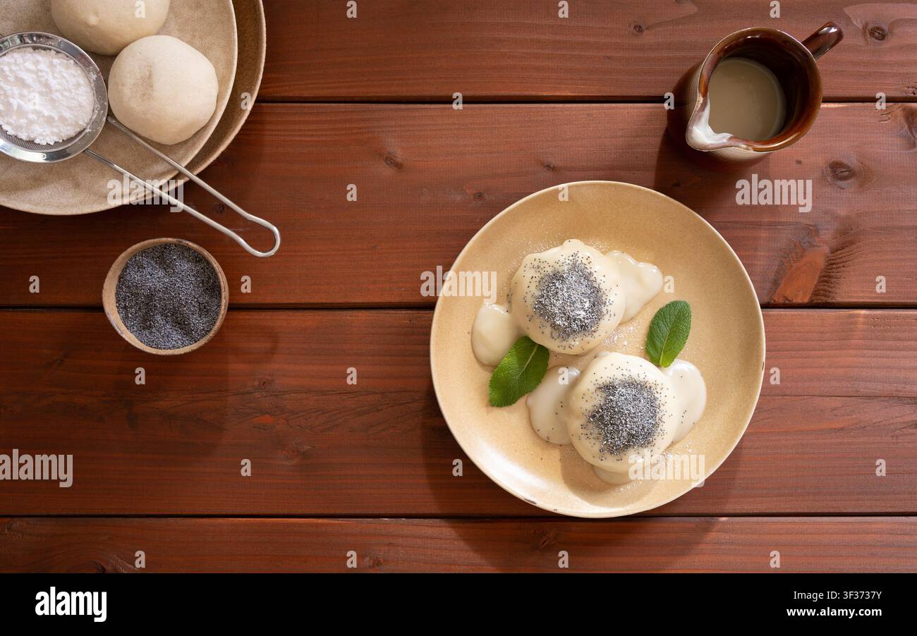 Rustikale Overhead-Komposition mit traditionellen deutschen Knödeln, serviert mit Vanillesauce und frischer Minze Stockfoto