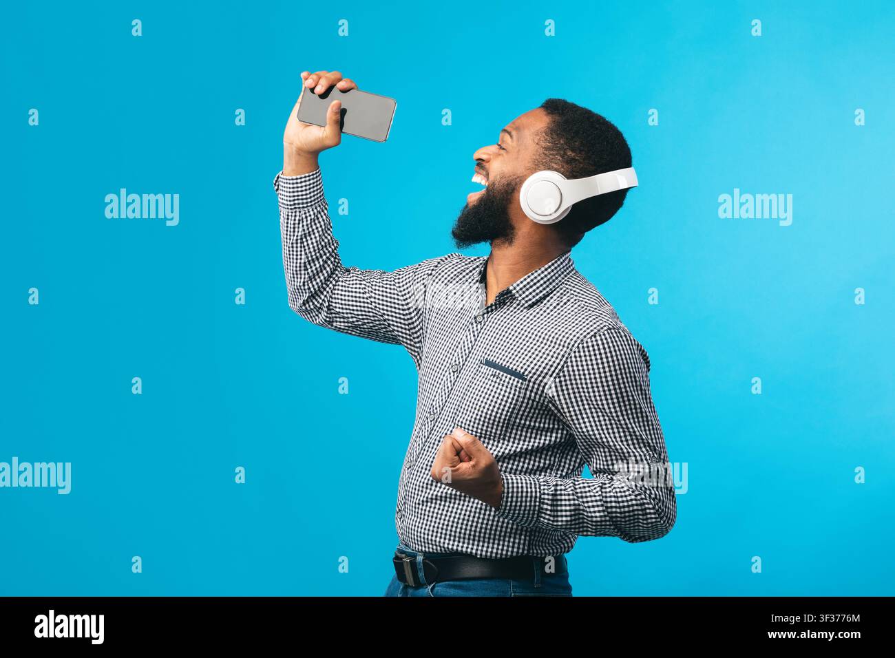 Afro Mann singt mit Smartphone als Mikrofon Stockfoto