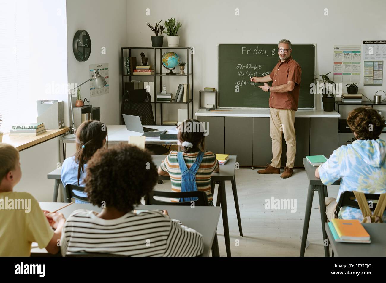 Verschiedene Teenager-Schüler lernen Mathe im Klassenzimmer mit Lehrerin Stockfoto