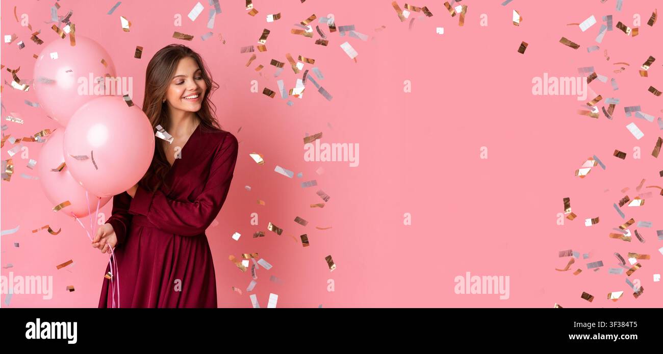 Fröhliche junge Frau hält Ballons und lächelt, Partysetting, Feiertagsthema Stockfoto