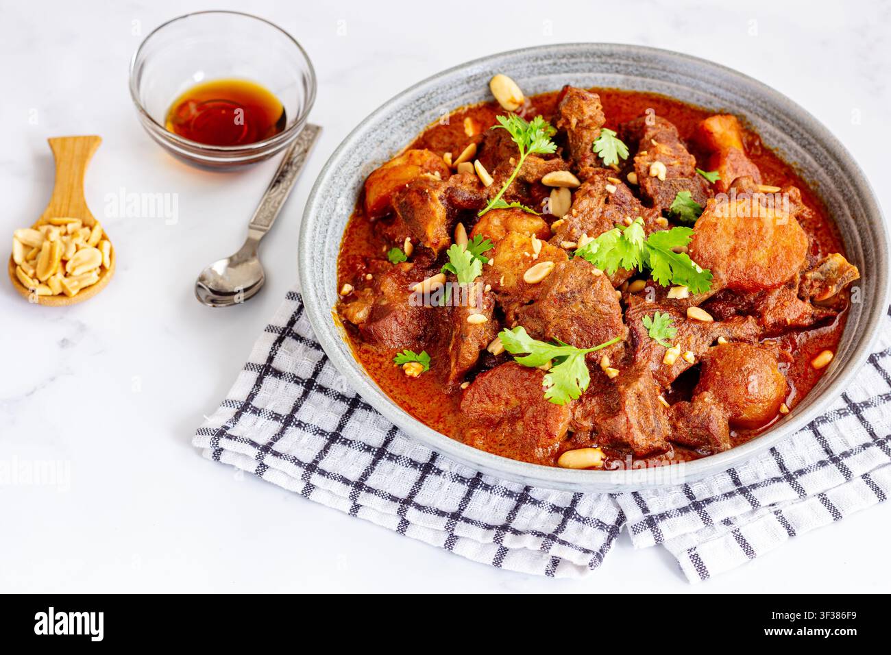 Traditionelles hausgemachtes thailändisches Massaman-Lammcurry, serviert in einer rustikalen Keramikschale mit Platz für Text Stockfoto