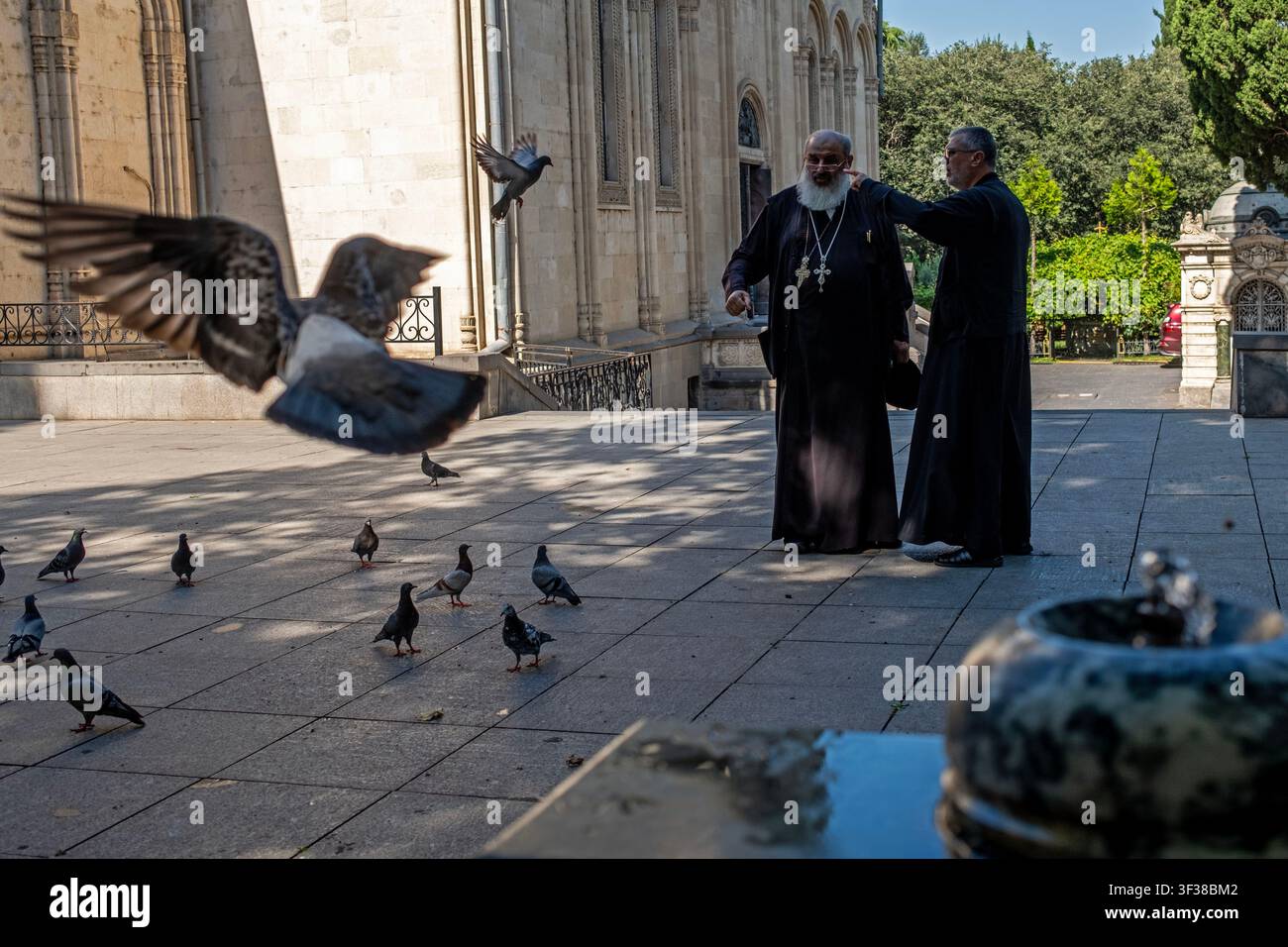 Tauben fliegen herum, während zwei Priester in einer Kirche in Tbilissi, Georgien, am 22. Juli 2026 plaudern. (Foto von Moe Zoyari/Sipa USA) Stockfoto
