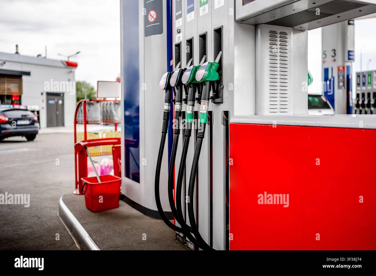 Grüne Kraftstoffpumpdüsen, die auf einem Außengelände einer Tankstelle für das Betanken von Fahrzeugen aufgereiht sind Stockfoto