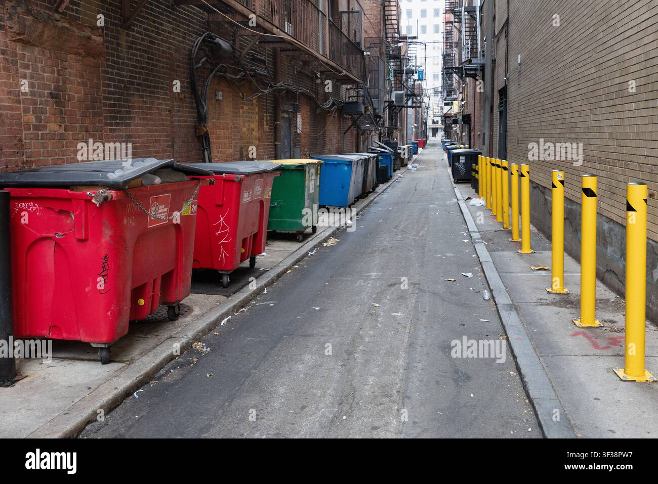 Dienstgasse gesäumt von Müllcontainern, Feuerleitern und gelben Sicherheitsbollwerken im Back Bay Viertel von Boston, Massachusetts, USA. Stockfoto