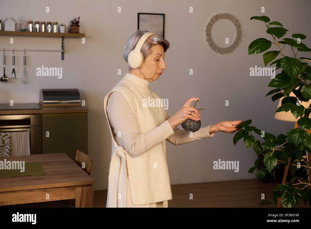 Eine anmutige Seniorin trägt Parfüm auf, während sie zu Hause Musik hört Stockfoto