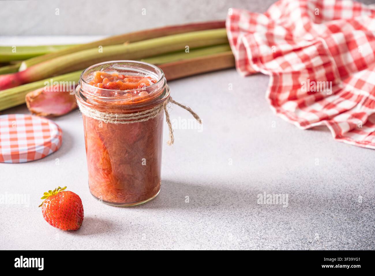 Hausgemachte Erdbeer-Rhabarber-Marmelade in einem Glas mit frischen Erdbeeren Stockfoto