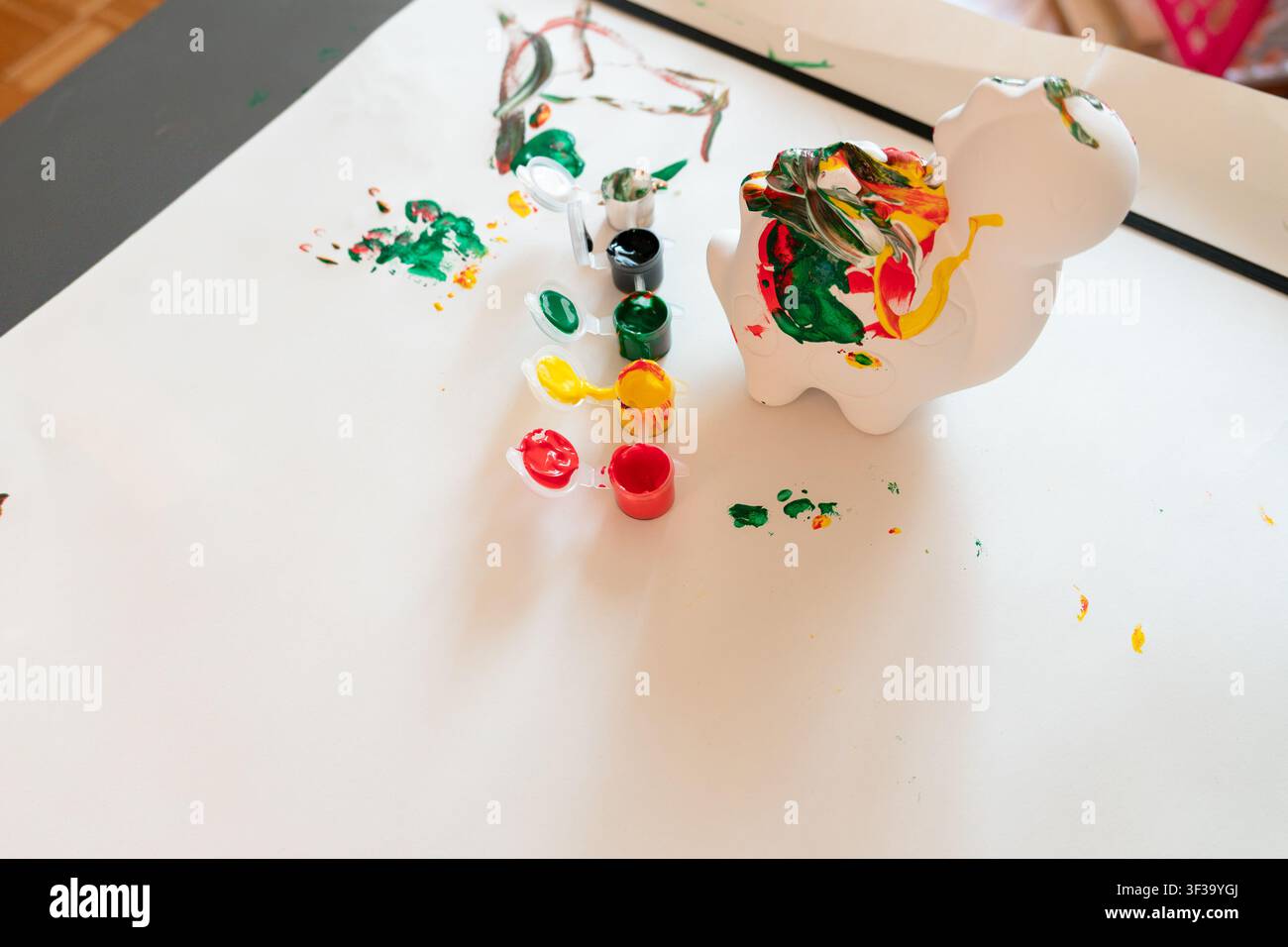 Bemalte Dinosaurier-Figur mit bunten Bastelfarben auf weißem Aktivitätstisch Stockfoto