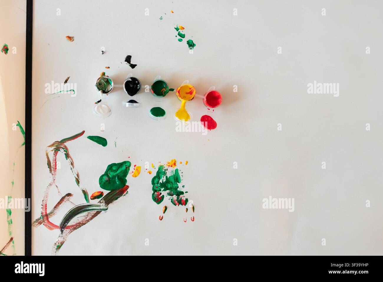Bunte Acrylfarbenpalette mit Pinselstrichen auf einem Basteltisch nach einer Kinderkunstaktivität. Stockfoto
