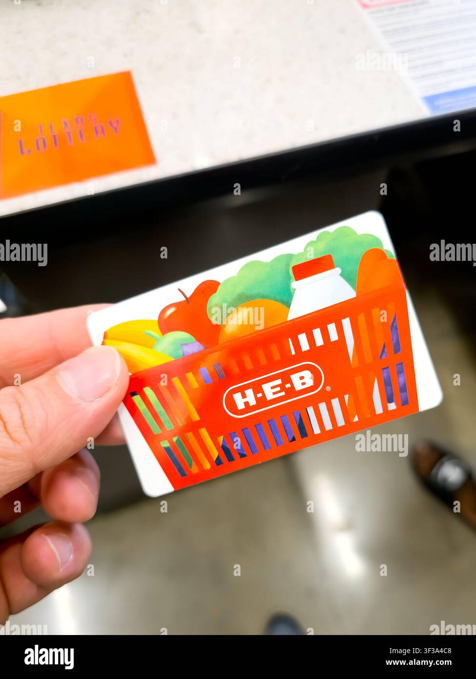 PLANO, TX, 2026 - 12. JULI 2026: - Eine Hand hält eine H-E-B-Giftkarte über einer Supermarktkasse. H-E-B ist eine beliebte Supermarktkette, die für Stockfoto