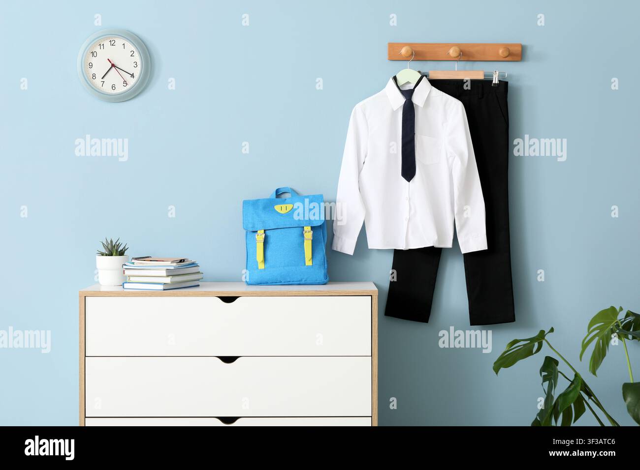 Schuluniform und Rucksack eines Kindes hängen an der Wand Stockfoto