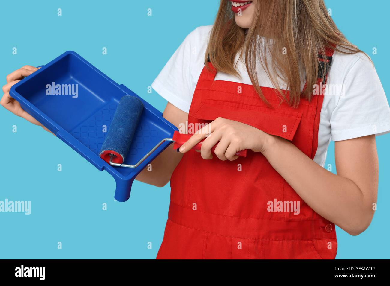 Malerin mit Malerwalze und Tablett auf blauem Hintergrund Stockfoto