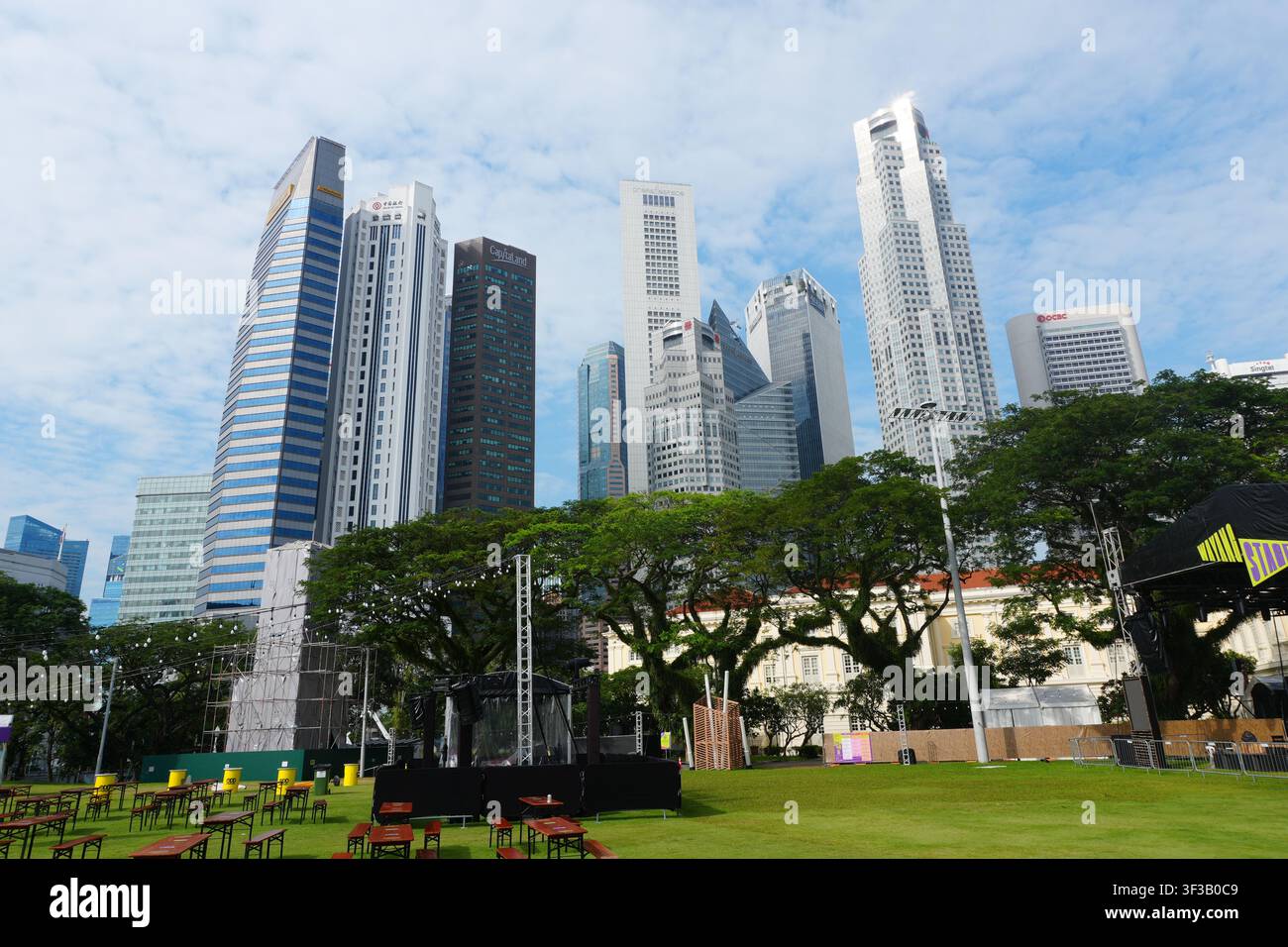 Breite Ansicht Singapur CBD Hochhaustürme Grünpark Rasen Outdoor-Event-Bestuhlung Tropische Bäume Stockfoto