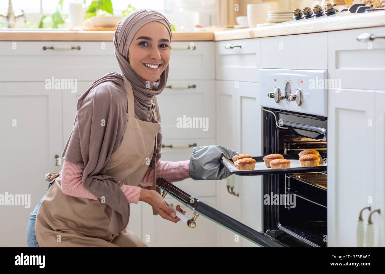 Muslimische Hausfrau. Porträt Einer Lächelnden Frau Im Hijab Baking In Kitchen Stockfoto