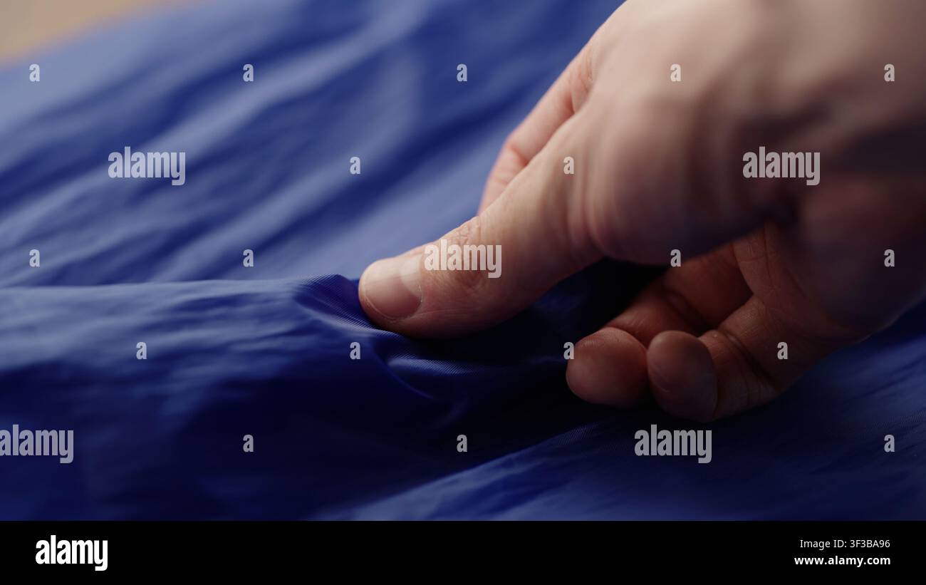 Männerhand prüft blauen Kunststofftaschenstoff Stockfoto