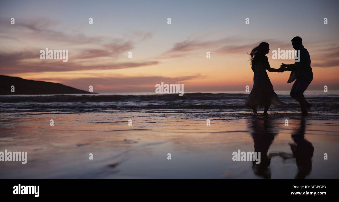 Silhouette, Paar und Tanz am Strand für Reisen, Feier und romantisches Date im Urlaub. Raum, Sonnenuntergang und Menschen am Meeresufer mit Lächeln Stockfoto