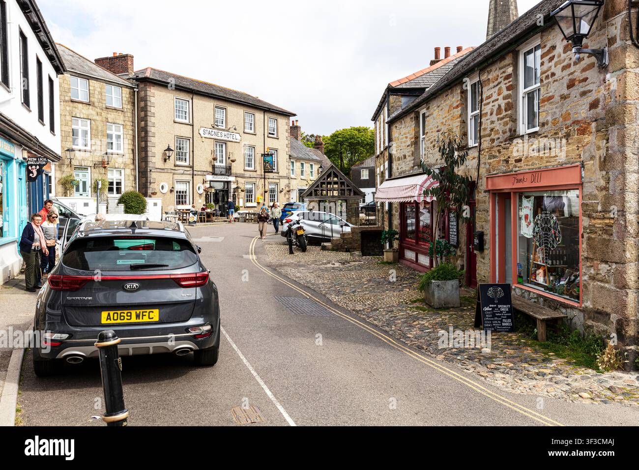 Eine Straßenszene in St. Agnes, Cornwall, mit dem St. Agnes Hotel und umliegenden Steinbauten in traditioneller Architektur. Parkende Autos säumen Stockfoto