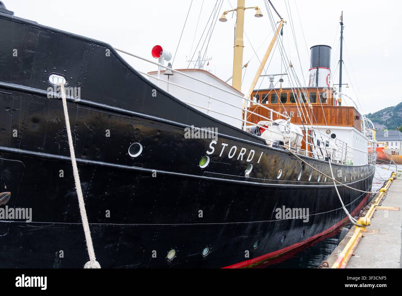 Klassisches norwegisches Dampfschiff Stord I, das in Bergen, Vestland, vertäut ist und an einem bewölkten Tag seinen eleganten schwarzen Rumpf und die hölzerne Aufbauten zur Schau stellt. Stockfoto