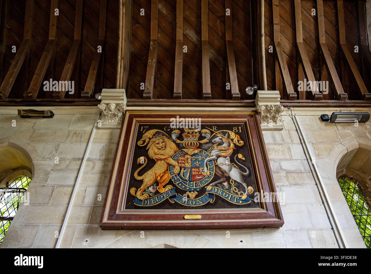 Heraldisches Wappenpaneel mit Löwe und Einhorn, montiert an einer Steinmauer unter einer hölzernen Balkendecke in Christ Church East Kennet Stockfoto