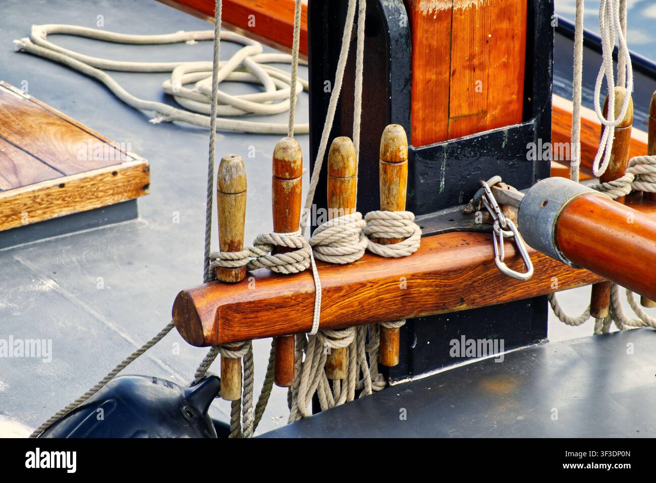 Holzschlingen, die ordentlich aufgerollte Seile auf einem Bootsdeck halten, betonen Segeltradition und Handwerkskunst Stockfoto