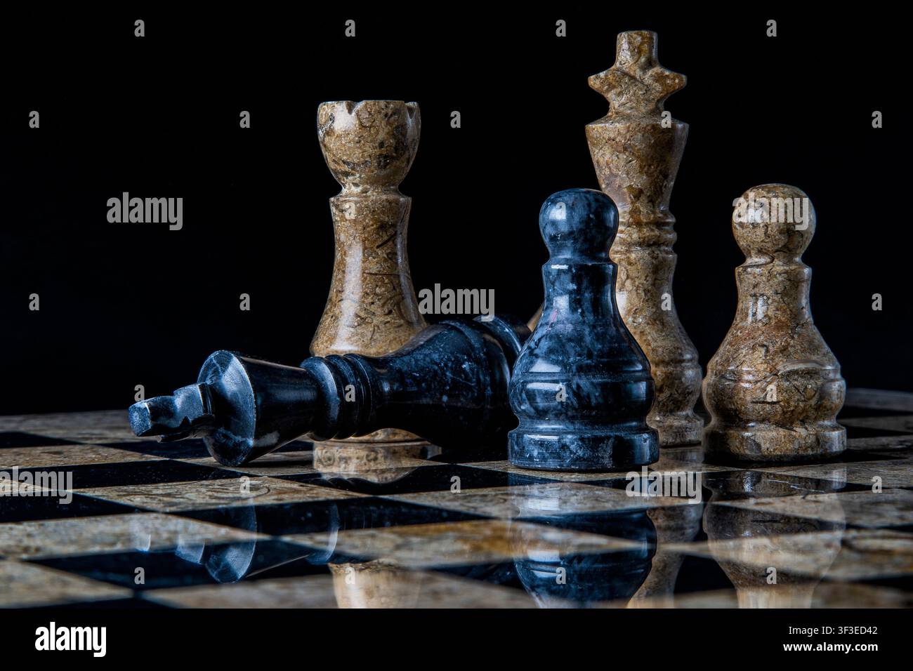 Schachmatt Spiel vorbei. Der König liegt zur Aufgabe da. Schönes Marmorschachset mit Reflexionen auf dem Brett und schwarzem Hintergrund. Stockfoto