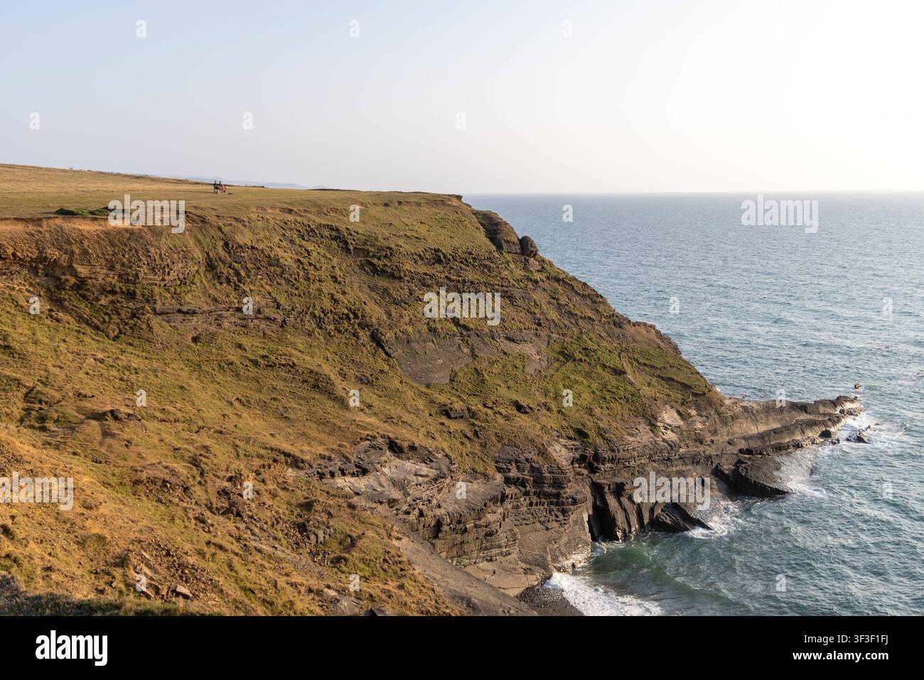 Cornwall 2026 Bude, England - 18.7.2026: Zwei Männer sitzen auf einer Parkbank mit Blick auf die Klippen und Küstenpfade von Bude in Cornwall. England Stockfoto