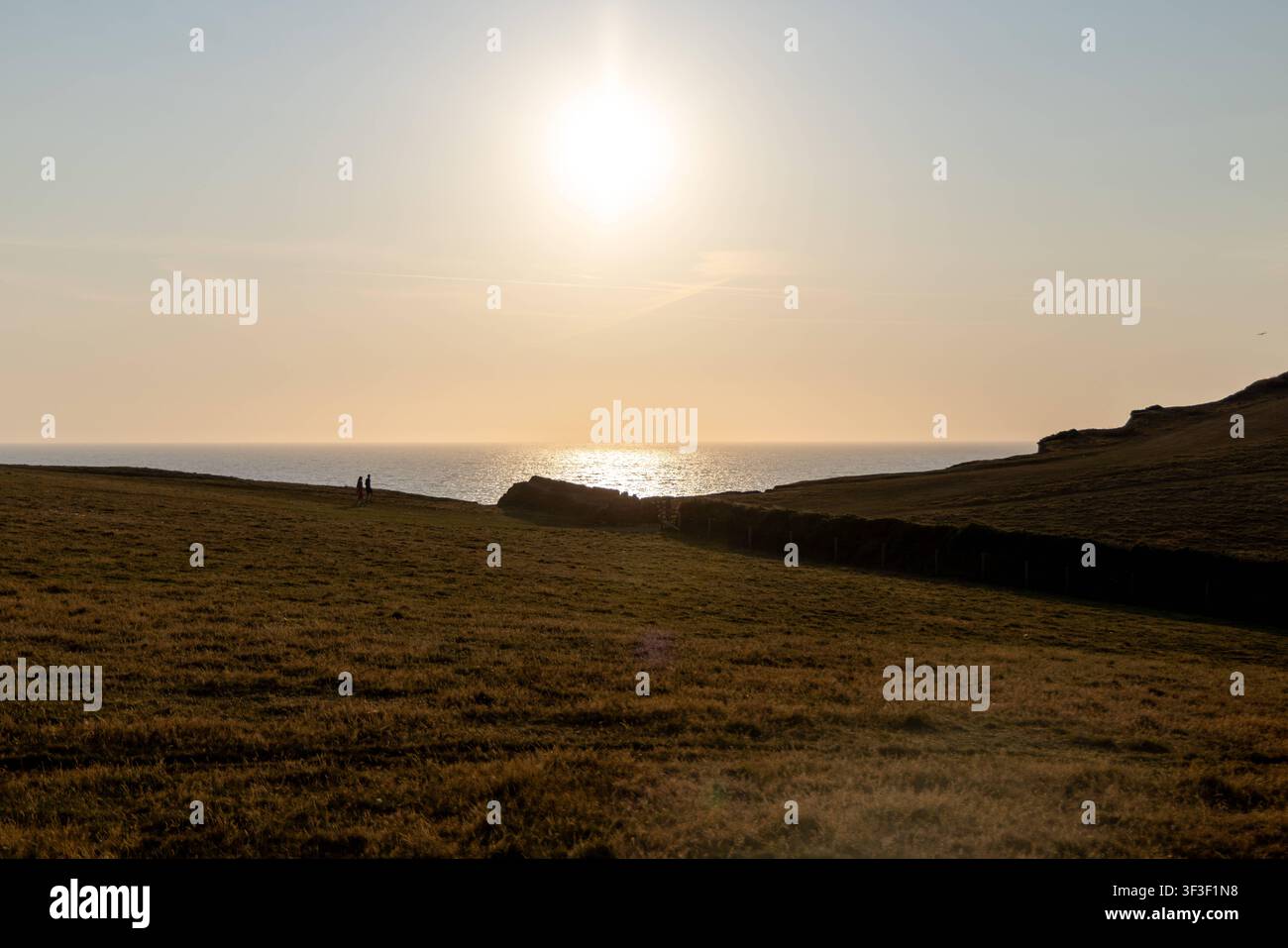 Cornwall 2026 Bude, England - 18.7.2026: Zwei Männer sitzen auf einer Parkbank mit Blick auf die Klippen und Küstenpfade von Bude in Cornwall. England Stockfoto