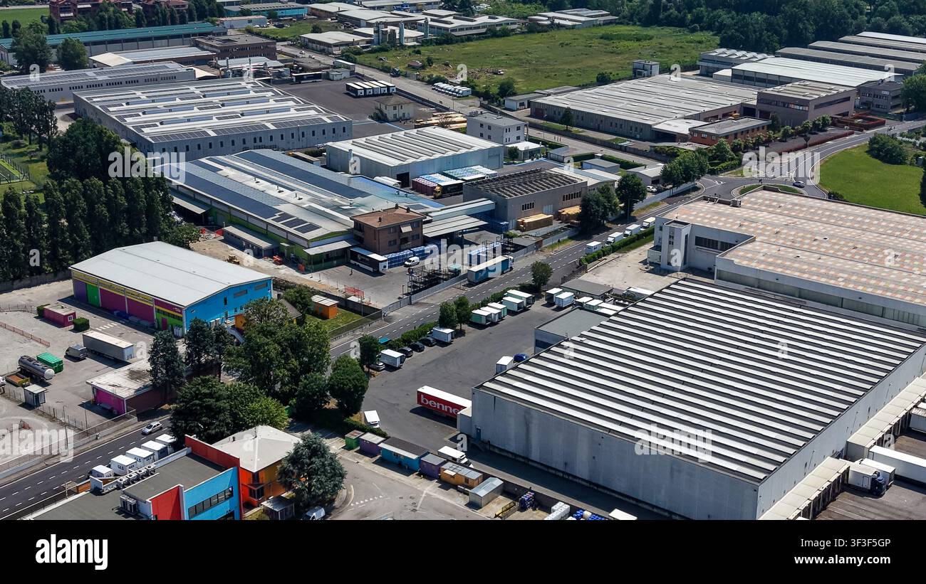 Luftaufnahme eines gewerblichen Industrieparks und Logistikzentrums mit großen Lagerhallen, Ladezonen, Lastwagen und asphaltierten Zufahrtsstraßen in Tribiano, Lombardei Stockfoto