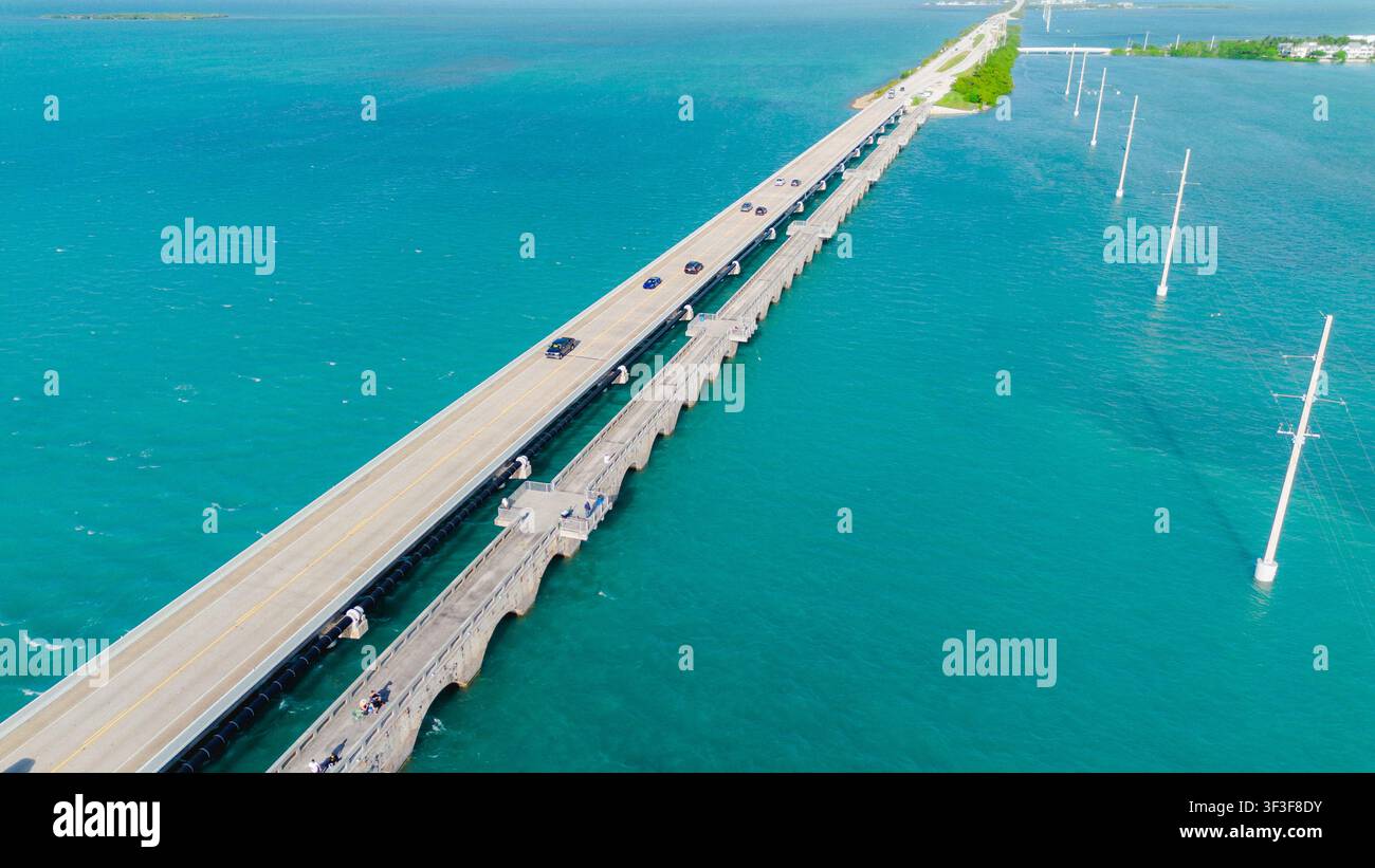 Luftbild der Seven Mile Bridge, die die türkisfarbenen Gewässer der Florida Keys überspannt, mit Autos, die entlang der Autobahn fahren, und Strommasten im Meer Stockfoto