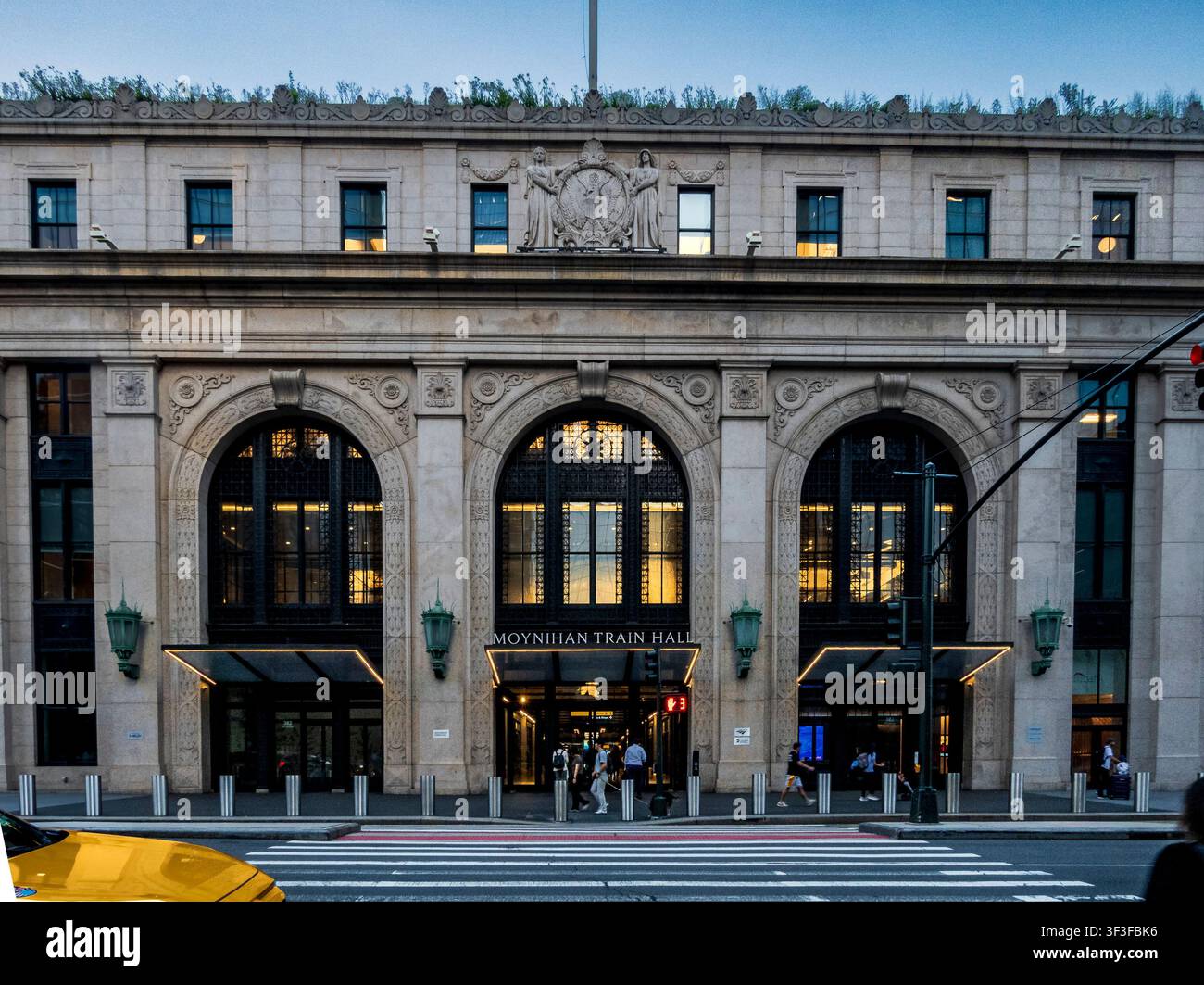 New York, NY - USA - 20. Jul 2026 Symmetrische Fassade des Moynihan Train Hall in New York City in der Dämmerung, mit beleuchteten Bogensch Fenstern und Eingang als p Stockfoto