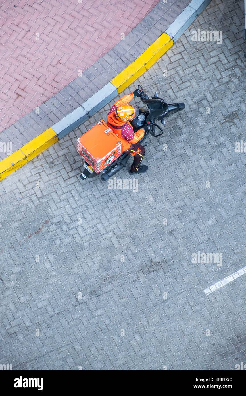 Talabat Delivery Service Lieferant auf einem Motorrad durch den Stadtverkehr Stockfoto