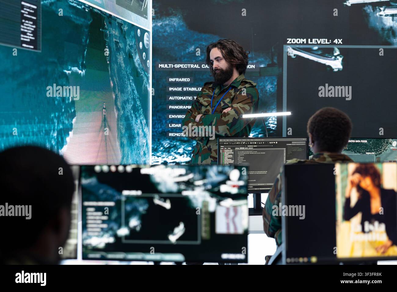 Militäranalyst bewertet feindliche taktische Aktivitäten auf Überwachungsbildschirmen, die auf einem großen Display angezeigt werden. Geheimdienstoffizier überprüft digitale Karten und führt georäumliche Analysen durch Stockfoto