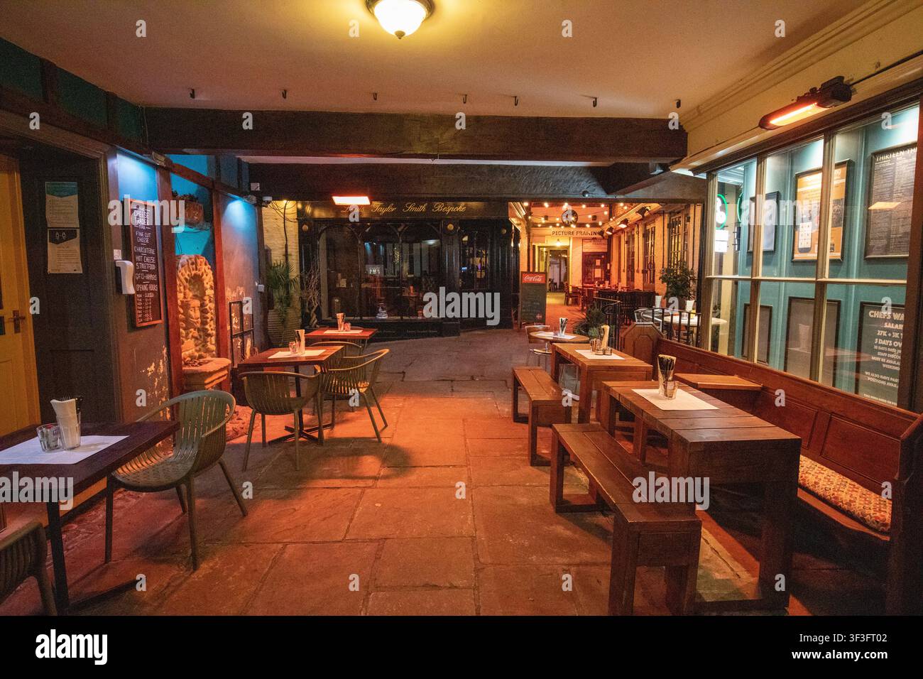 Gemütlicher Biergarten und Sitzbereich eines historischen Pubs in York bei Nacht, mit warmen Holzbank und stimmungsvoller Beleuchtung. Stockfoto