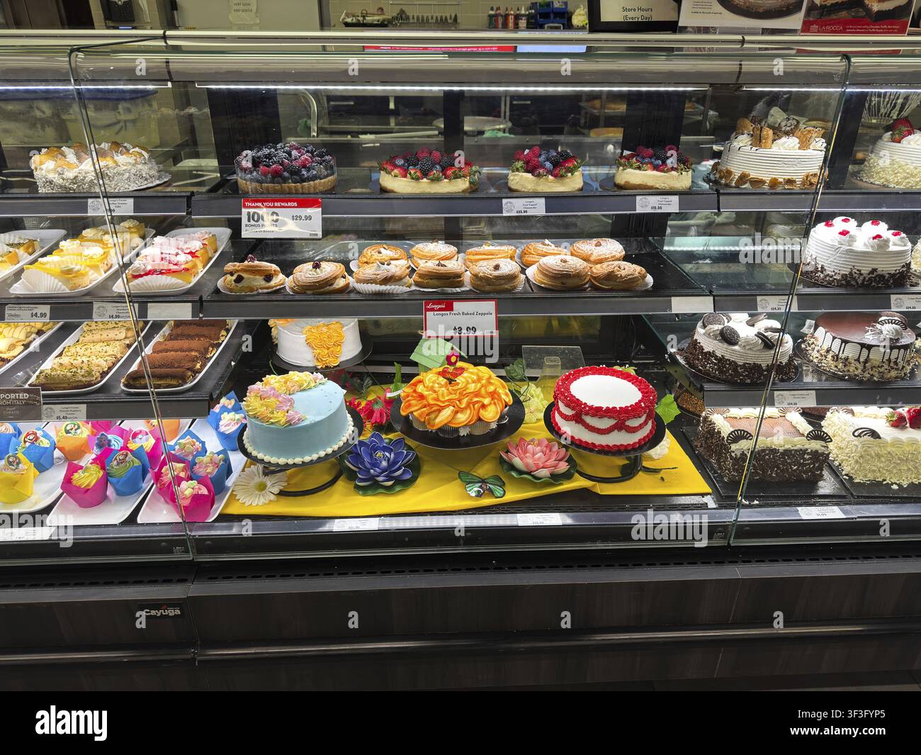 Farbenfrohe Backwarenauslage gefüllt mit Cupcakes, Macarons und Minikuchen, glänzenden Glasuren und gezogener Glasur, Obstkuchen und neuartigen Donuts Stockfoto
