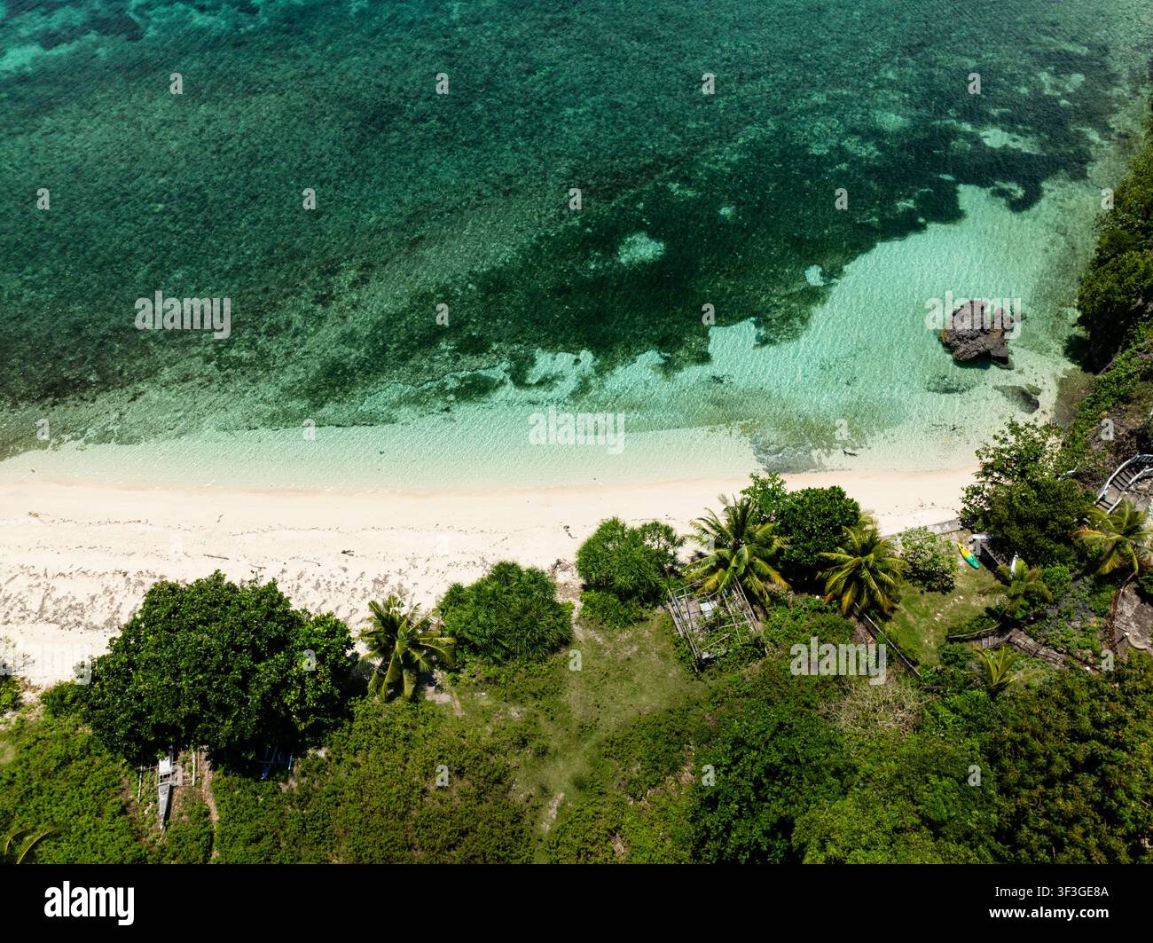 Abgeschiedene Strandbucht mit klarem türkisfarbenem Wasser und felsiger Küstenlinie. Camotes, Philippinen. Stockfoto