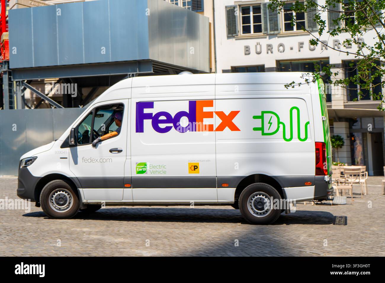 Weißer elektrischer FedEx-Lieferwagen fährt auf einer Kopfsteinpflasterstadtstraße in Zürich, Schweiz - 23. Juni 2026 Stockfoto