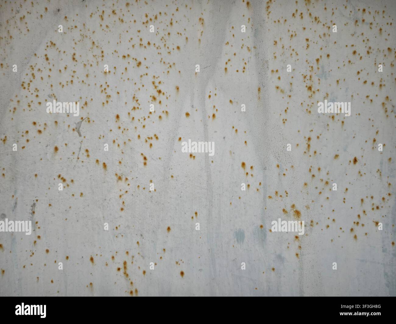 Eine Wand zeigt Rostflecken und eine raue Textur in einer Stadtszene, die tagsüber bei natürlichem Licht aufgenommen wurde. Stockfoto