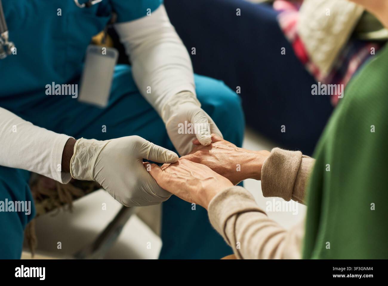 Arzt hält die Hände einer Seniorin während eines Hausbesuchs Stockfoto