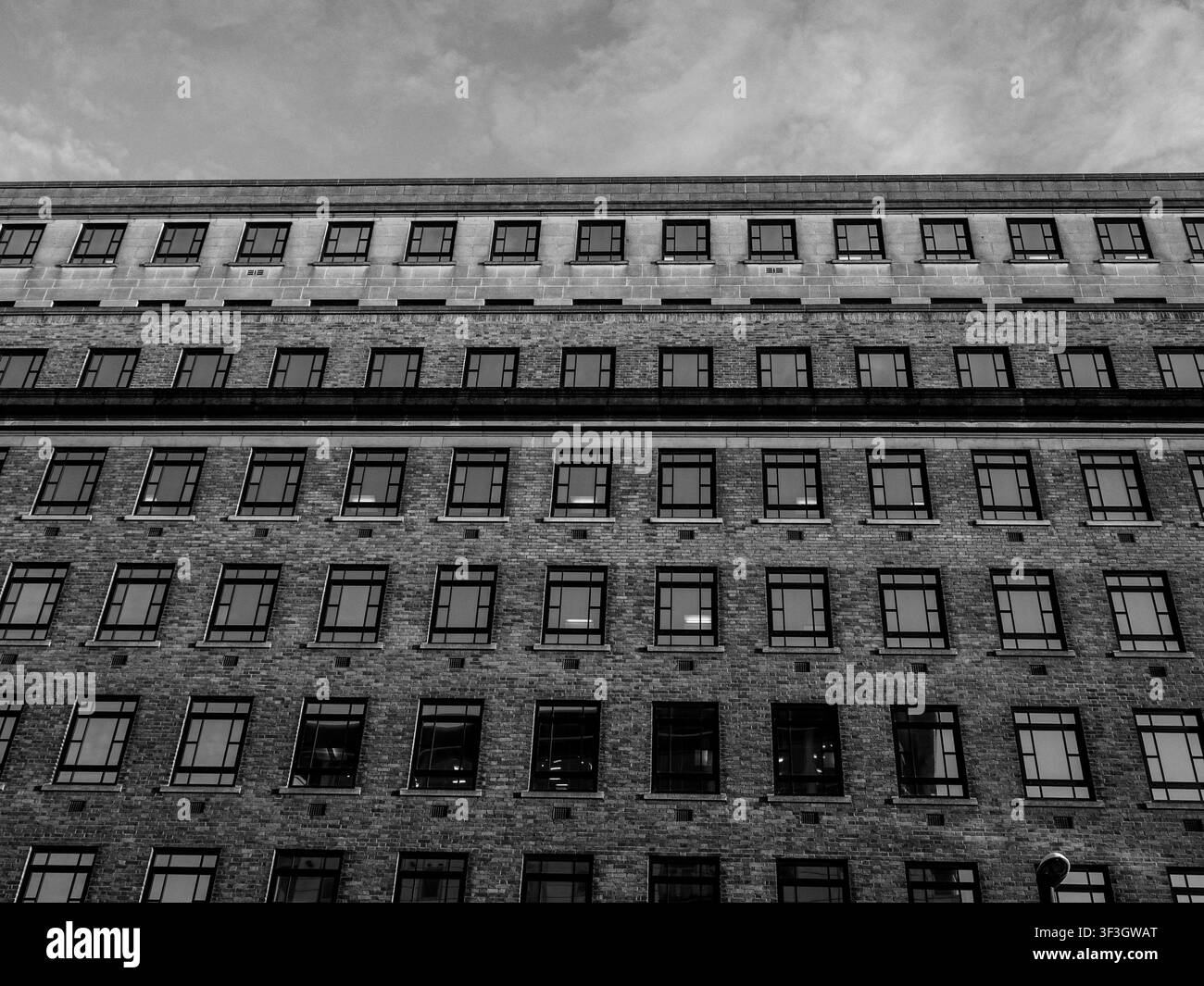 Backsteinfassade eines Bürogebäudes mit sich wiederholenden Fensterreihen in Schwarz und Weiß Stockfoto