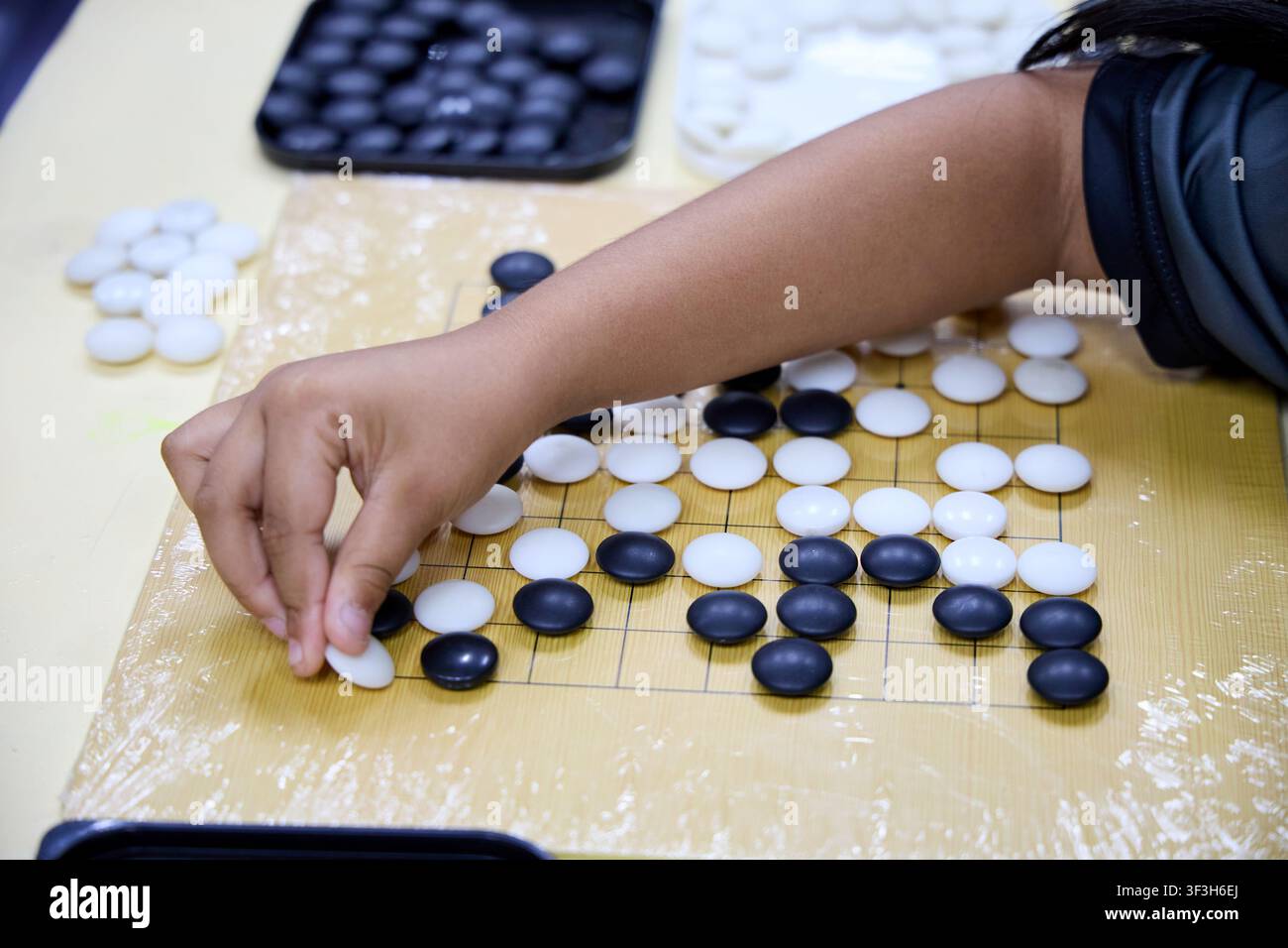 Kinder spielen Go-Brettspiel mit schwarzen und weißen Steinen Stockfoto